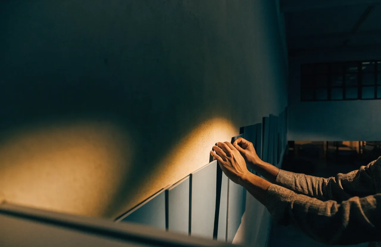 A dim interior at night with several blank slate mounting boards hung in a row, washed by a single warm light